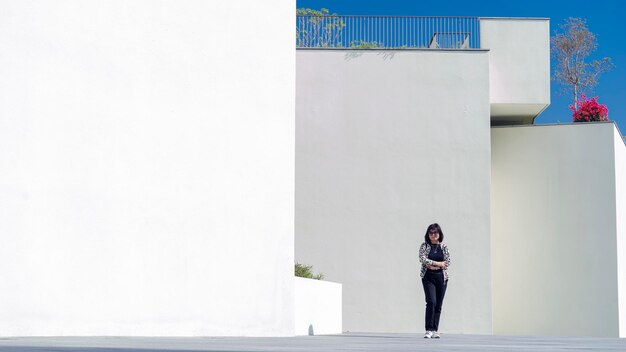 Foto lunghezza completa di una donna in piedi contro un muro bianco