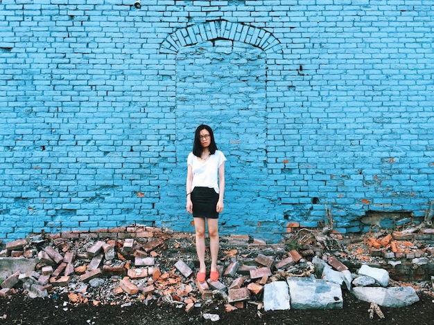 Photo full length of woman standing amidst bricks against blue wall