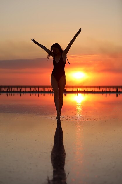 Full length of woman standing at beach against sky during sunset