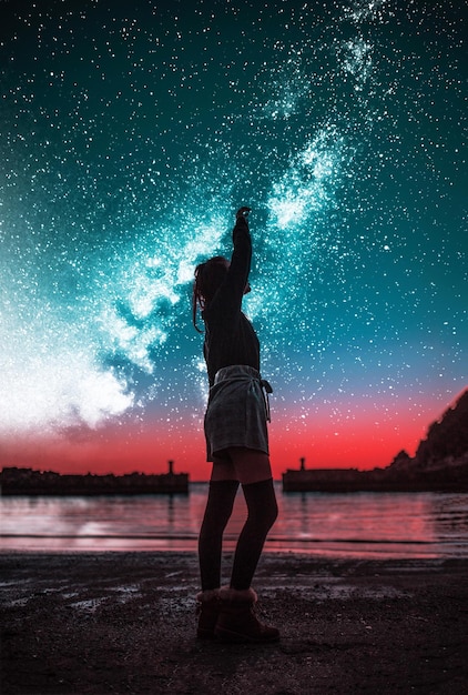 Foto lunghezza completa di una donna in piedi sulla spiaggia contro il cielo stellato