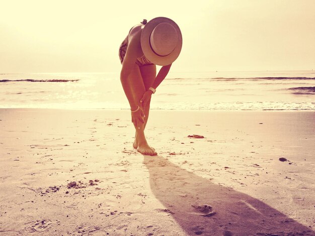 Foto lunghezza completa di una donna in piedi sulla spiaggia