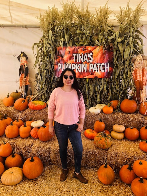 Photo full length of woman standing by pumpkins