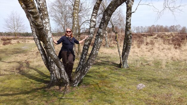 Foto lunghezza completa di una donna in piedi vicino a un albero nella foresta