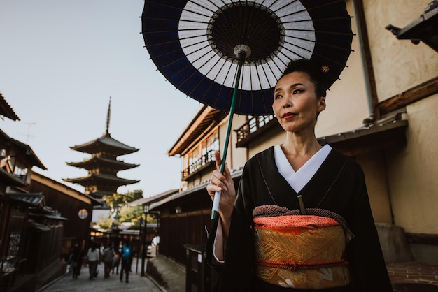 Photo full length of woman standing on footpath amidst buildings