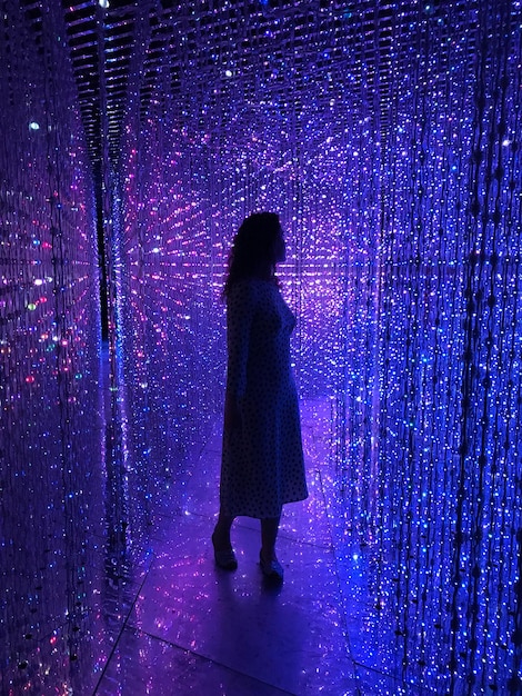 Foto lunghezza completa di una donna in piedi in un corridoio illuminato