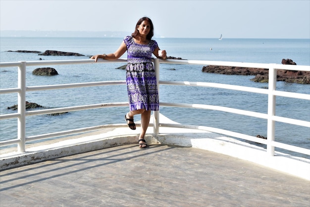 Full length of woman standing on railing against sea