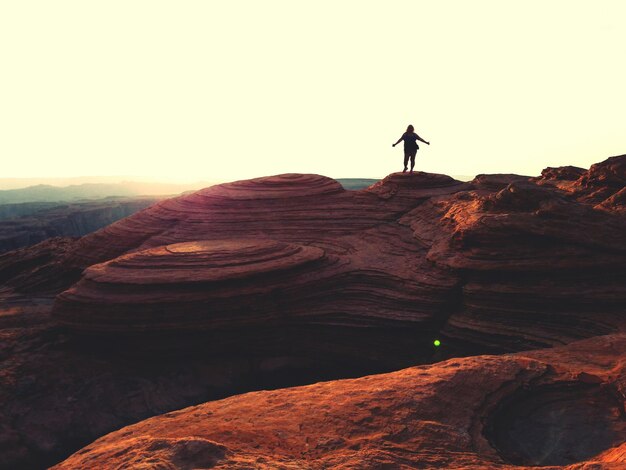 Full length of woman standing on rock formation against sky