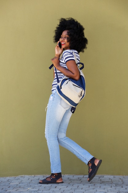 Full length woman talking on mobile phone and walking with bag