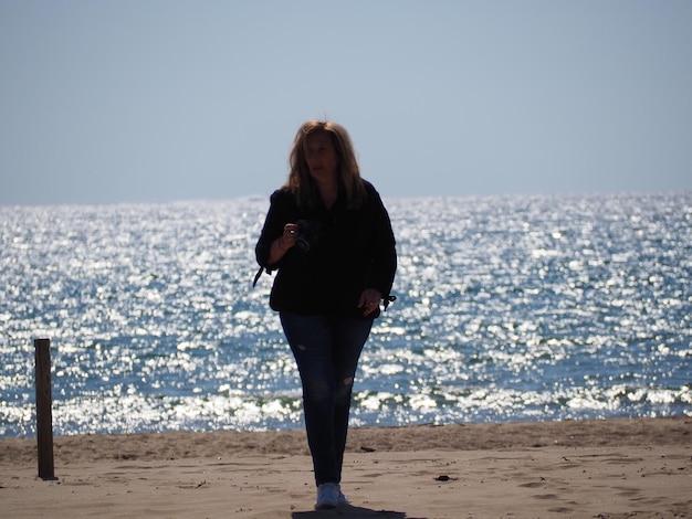 Full length of woman walking at beach against clear sky