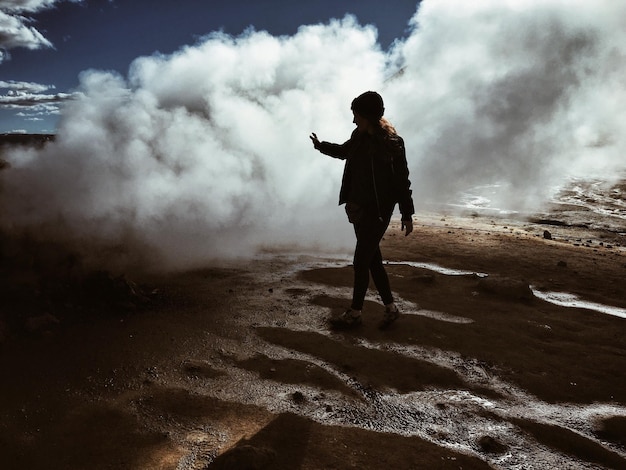 Photo full length of woman walking by geyser emitting smoke