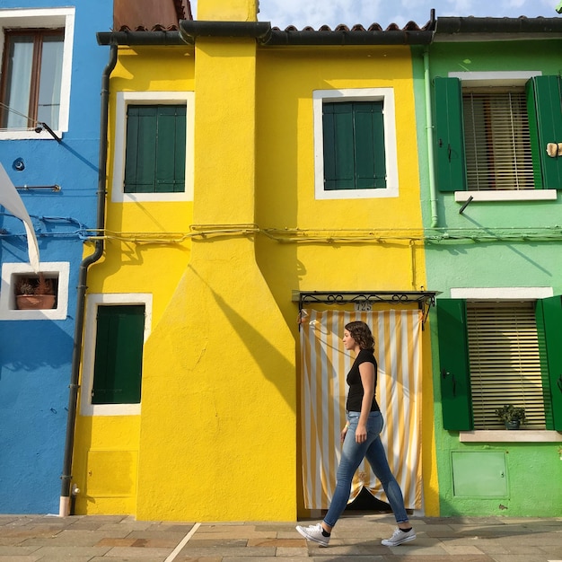 Photo full length of woman walking on sidewalk by yellow building