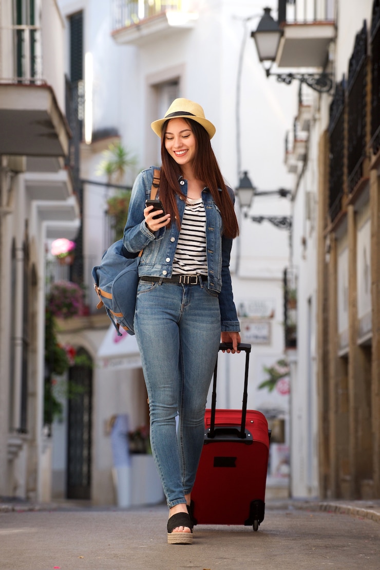Photo 携帯電話を持っている荷物で通りを歩く全身の女性
