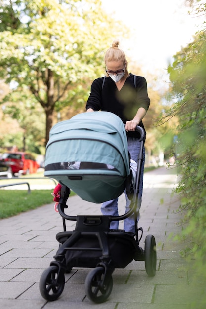 公園でベビーカーを乗せてマスクをかぶった女性の全身