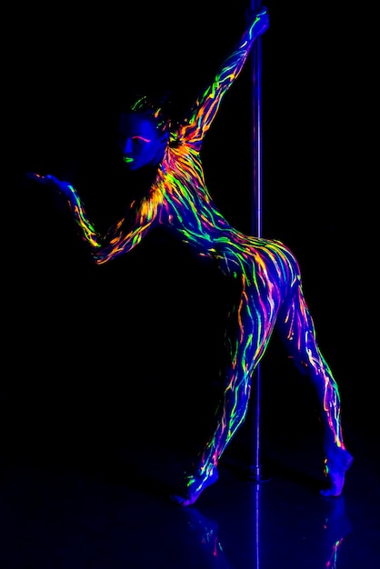 Photo full length of woman wearing neon clothing doing pole dance against black background