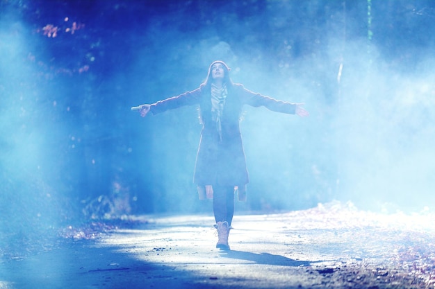 Full length of woman with arms outstretched standing on footpath during foggy weather