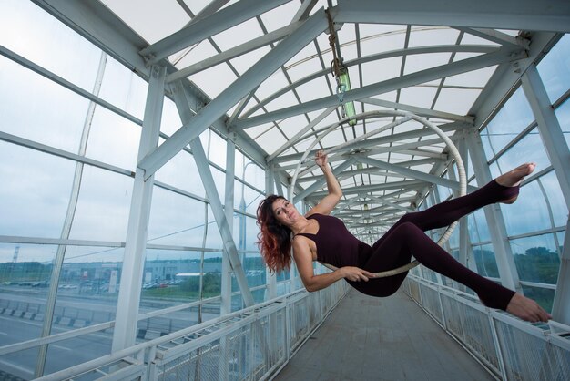 full length of woman with arms raised while standing on railing