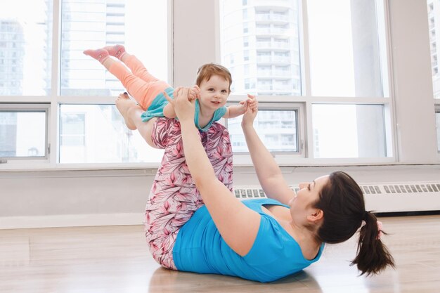 Full length of woman with daughter exercising on floor