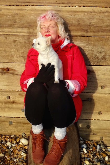 Full length of woman with dog sitting against wooden wall