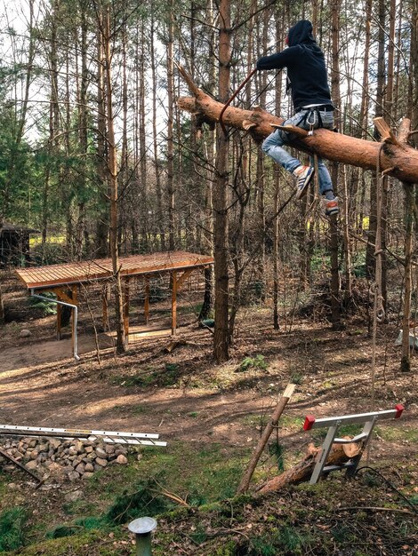 Foto lunghezza intera di un operaio che taglia un albero nella foresta