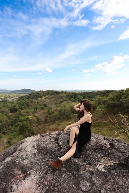 Full length young beautiful asian woman, long hair in black dress sitting in nature outdoors