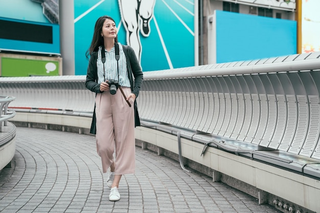 전체 길이 젊은 여성 사진 작가 카메라와 함께 다리에 산책 휴식. dslr 카메라에서 사진을 찍는 아름다운 아시아 여성 취미. 도시에서 휴가에 일본 여자입니다.