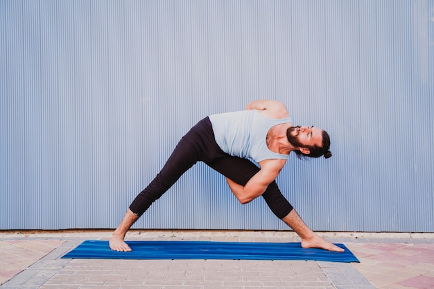 full length of young man exercising on exercise mat against wall