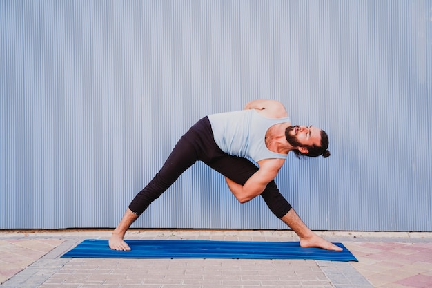 Full length of young man exercising on exercise mat against wall