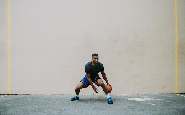 full length of young man playing basketball against wall