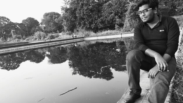 Full length of young man sitting by lake