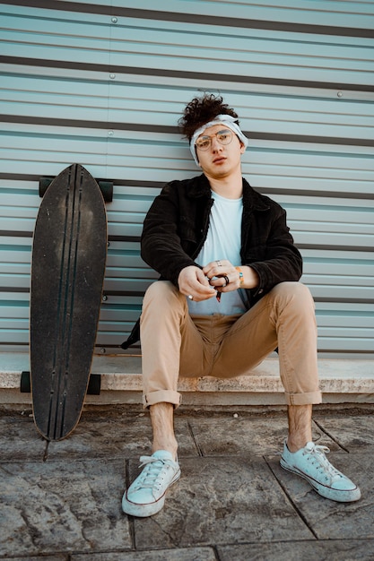 Photo full length of young man sitting on seat against wall