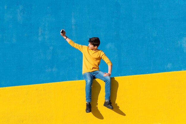 Full length of young man standing against yellow wall