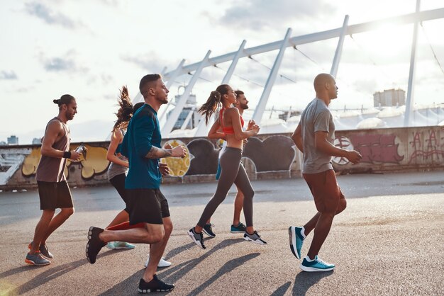 Full length of young people in sports clothing jogging outdoors