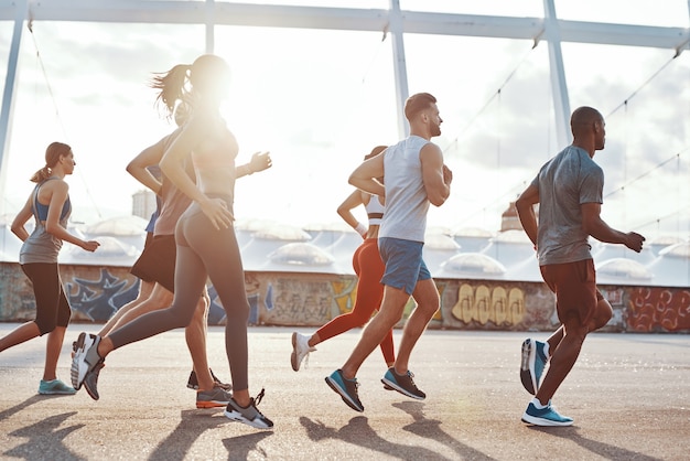 Full length of young people in sports clothing jogging outdoors