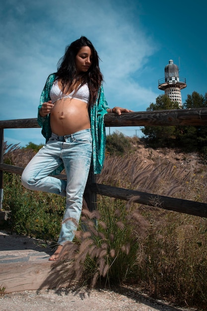 Foto lunghezza completa di una giovane donna incinta in piedi sulla terra contro il cielo