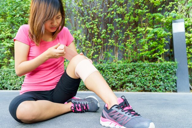 Photo full length of young woman applying adhesive bandage on leg