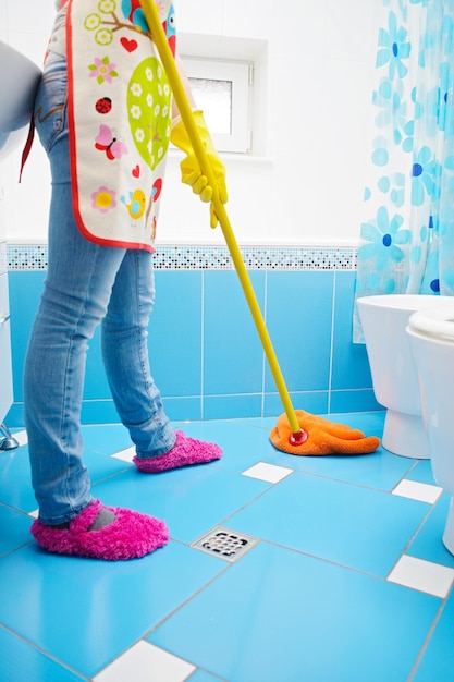 Full length of young woman cleaning ceramic floor of bathroom at home