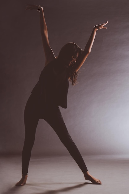 Foto tutta la lunghezza di una giovane donna che balla sullo sfondo nero.