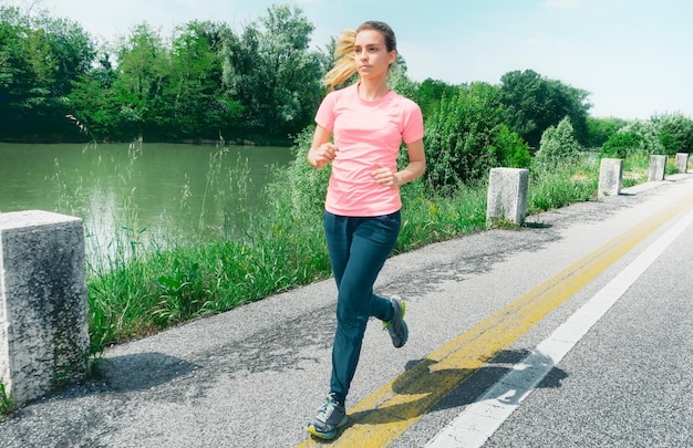 Foto lunghezza completa di una giovane donna che fa jogging lungo il fiume