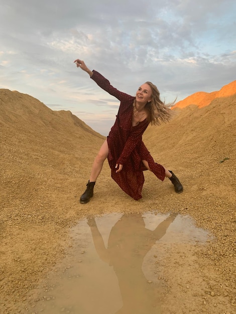 Foto lunghezza completa di una giovane donna che salta sulla sabbia in spiaggia