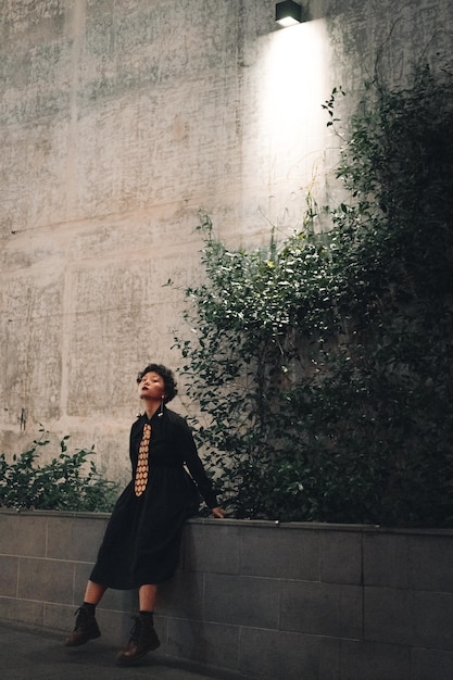 full length of young woman looking away against wall