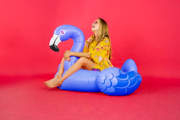 Full length of a young woman sitting against red background