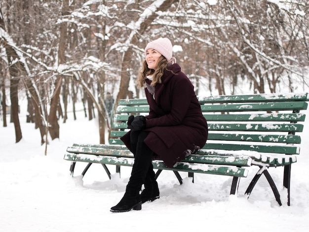 full length of young woman sitting on bench during winter