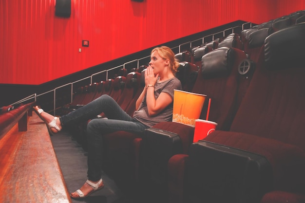 Foto lunghezza completa di una giovane donna seduta al teatro