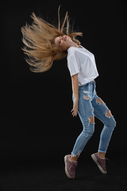 Full length of young woman standing against black background