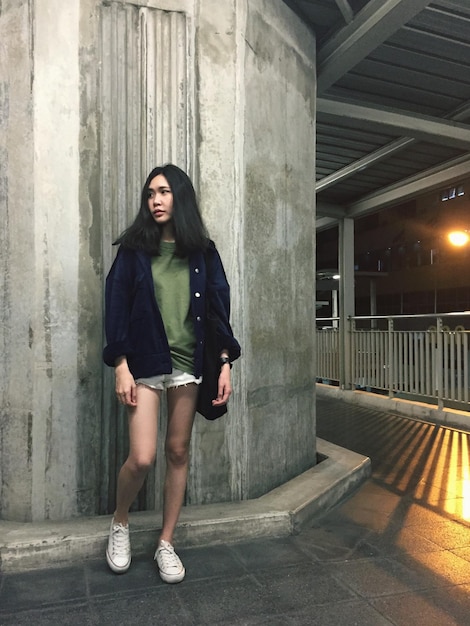Full length of young woman standing against wall