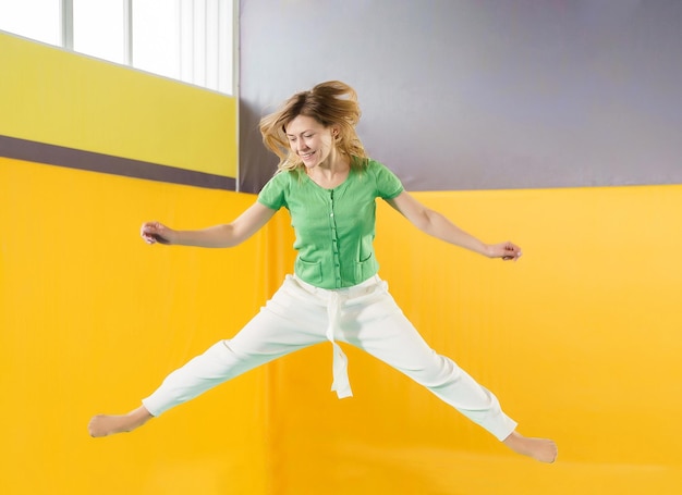 Full length of young woman standing against yellow wall