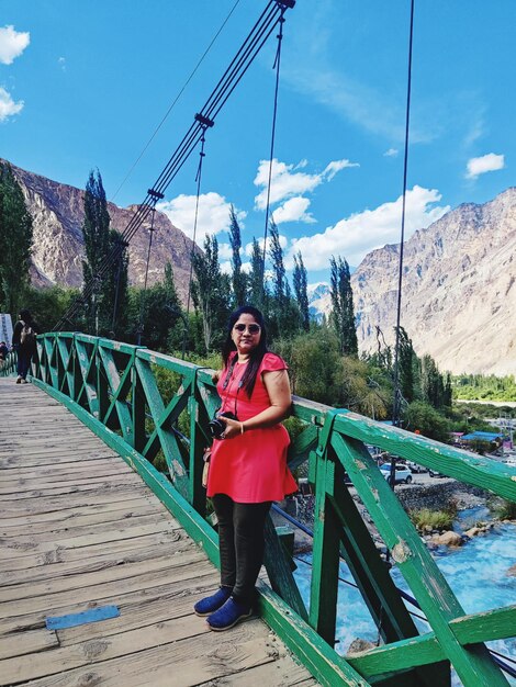 Photo full length of young woman standing on bridge against sky mountain