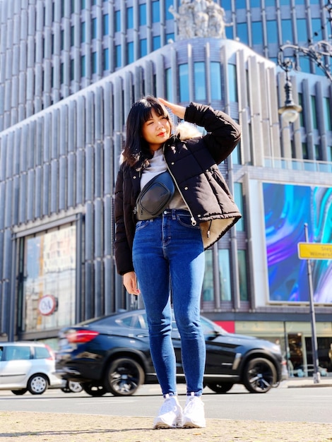 도시에서 서 있는 젊은 여성의 전체 길이