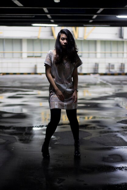 Photo full length of young woman standing on wet floor in parking lot