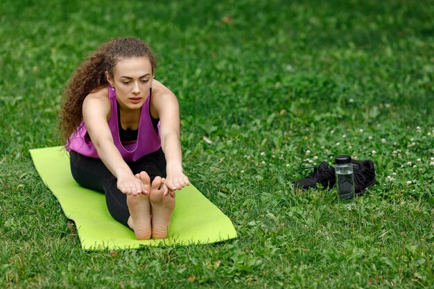 Foto lunghezza completa di una giovane donna che si allunga al parco